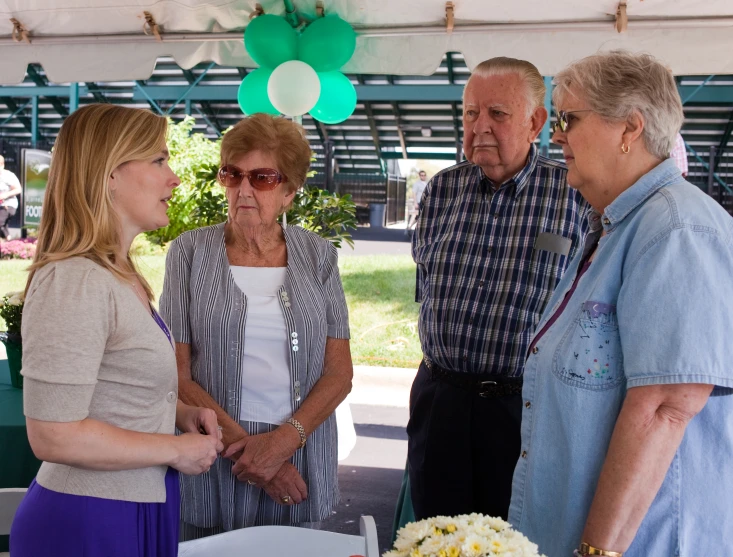 a group of people stand at a white table in front of an event tent