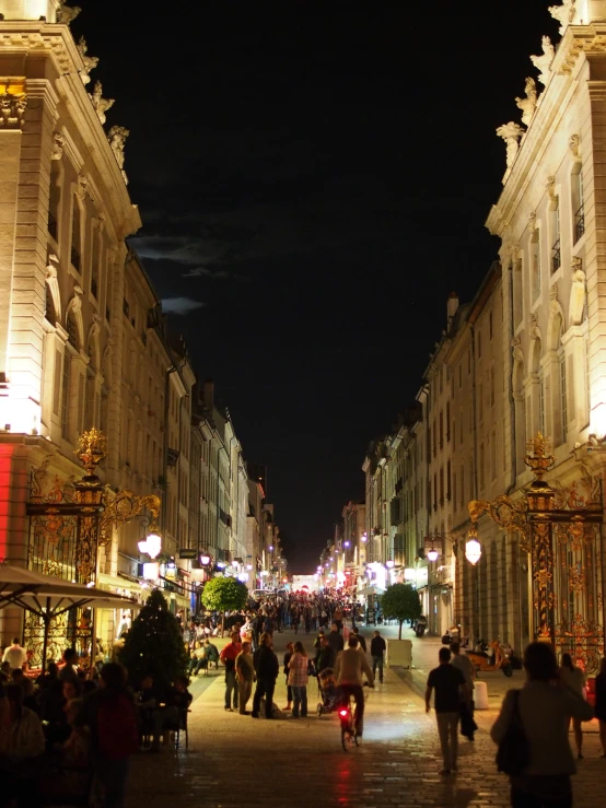 several people walk down a bricked street at night