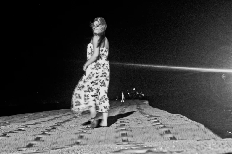 a girl is standing on a pier at night