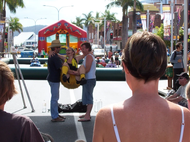 two people sitting on a chair in front of a carnival attraction