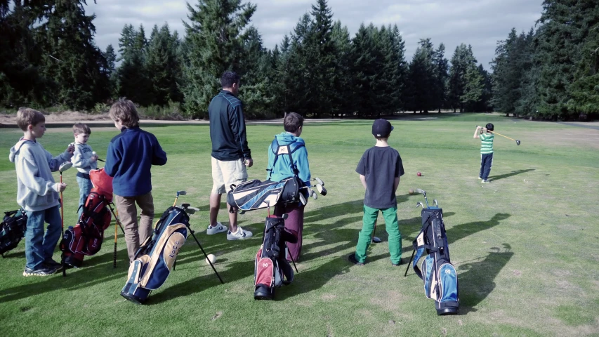 several people with golf equipment standing in the grass