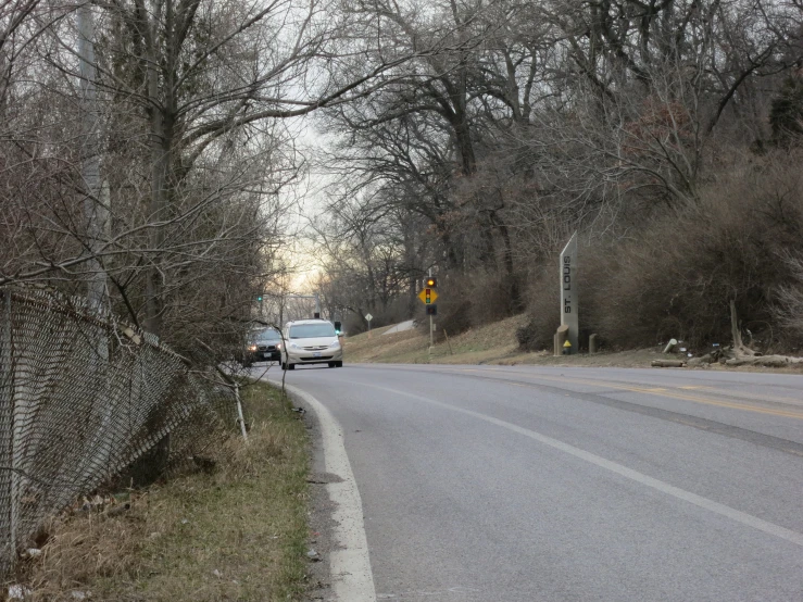 a road lined with tree line next to a parking lot