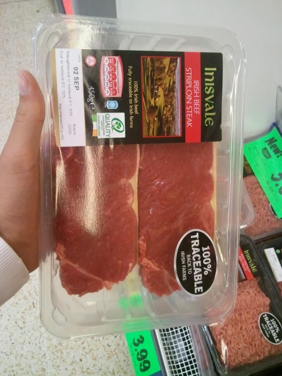 a person's hand holding a package of meat