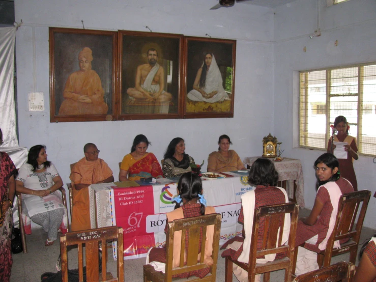 people seated around tables with pictures hanging on the wall