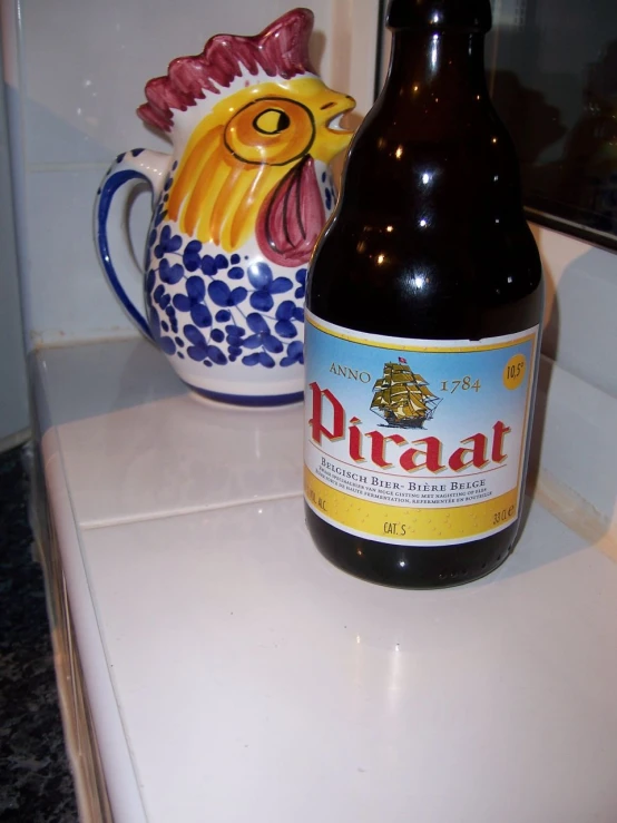 a beer bottle next to a decorated rooster ceramic pot