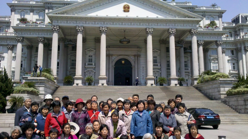 group of asian children posing in front of a white mansion