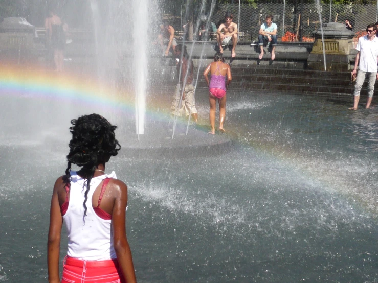 woman at the fountains watching several children play