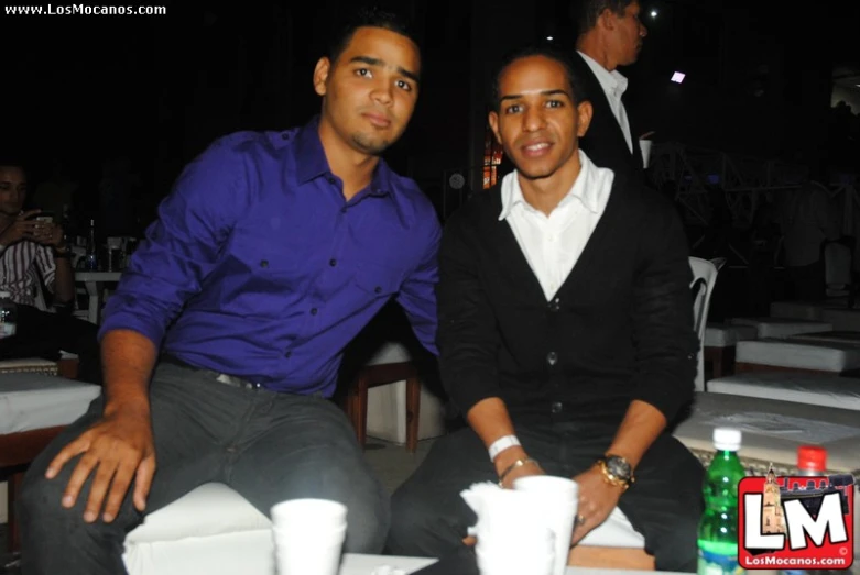 two men pose for the camera while sitting in chairs