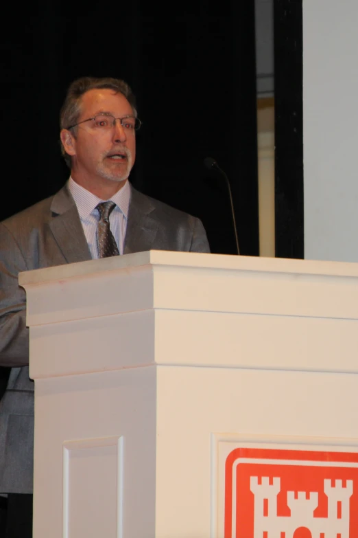 a man standing in front of a microphone behind a podium