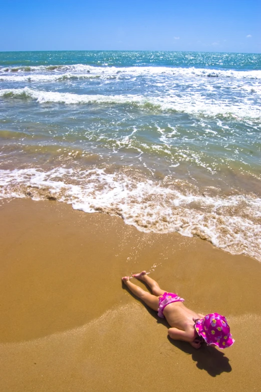 a young child is laying down on the beach