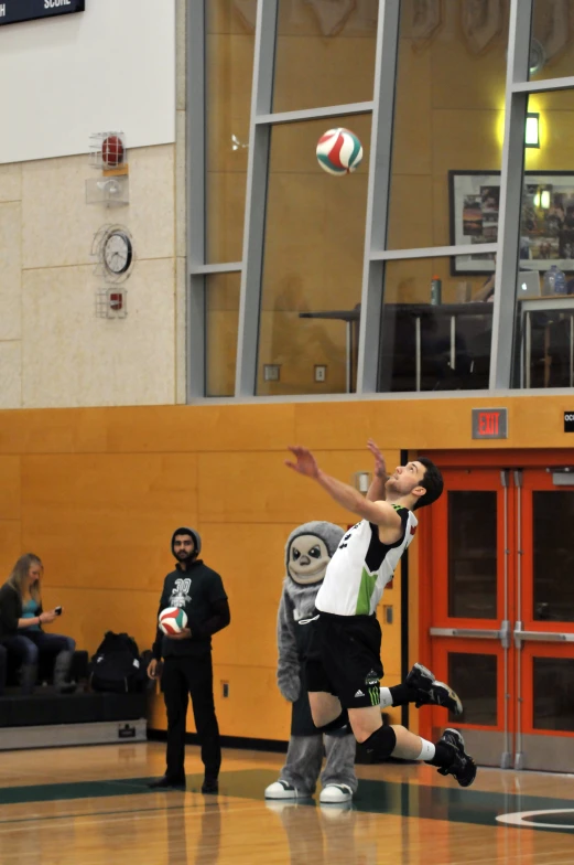 men playing a game of volleyball with mascot costume on