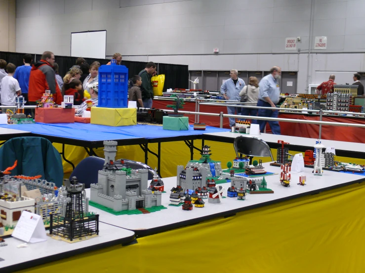 table full of legos with people standing around them