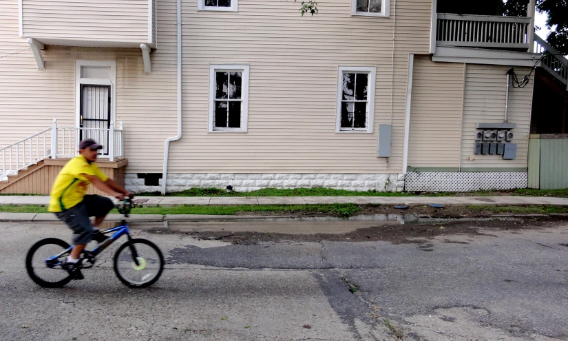 a man in yellow shirt riding bicycle on the street