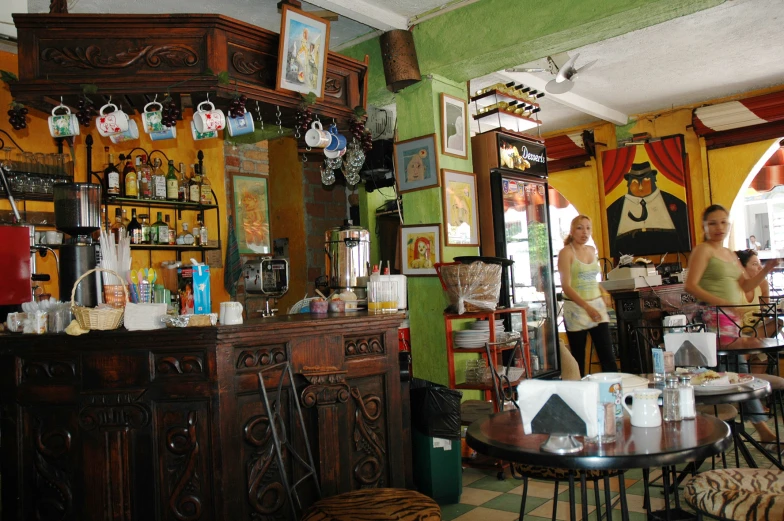 two women are standing by a bar with many bottles on it