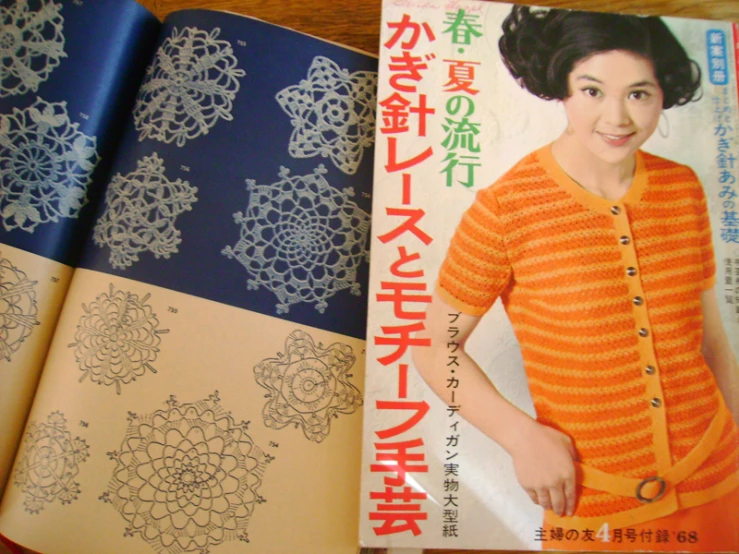 an asian woman wearing an orange jacket next to a book