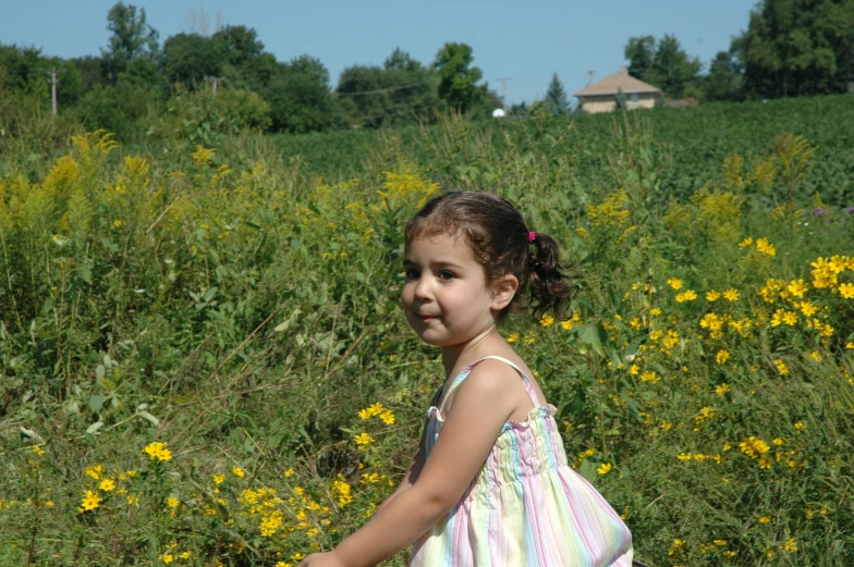 a girl standing in a field with yellow flowers