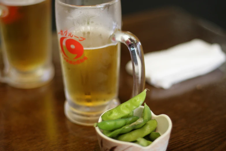 peas are steamed in a small bowl and a pint glass with a sakebe