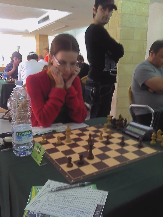 a woman sitting at a table while playing chess