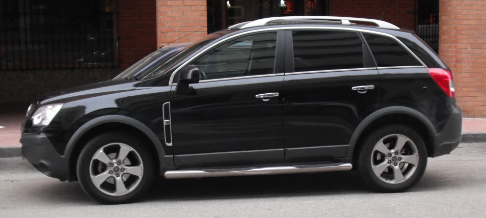 an suv parked outside on the street next to a sidewalk