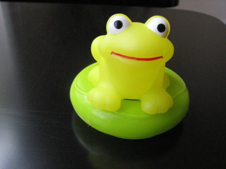 a cute yellow frog sitting on a black table