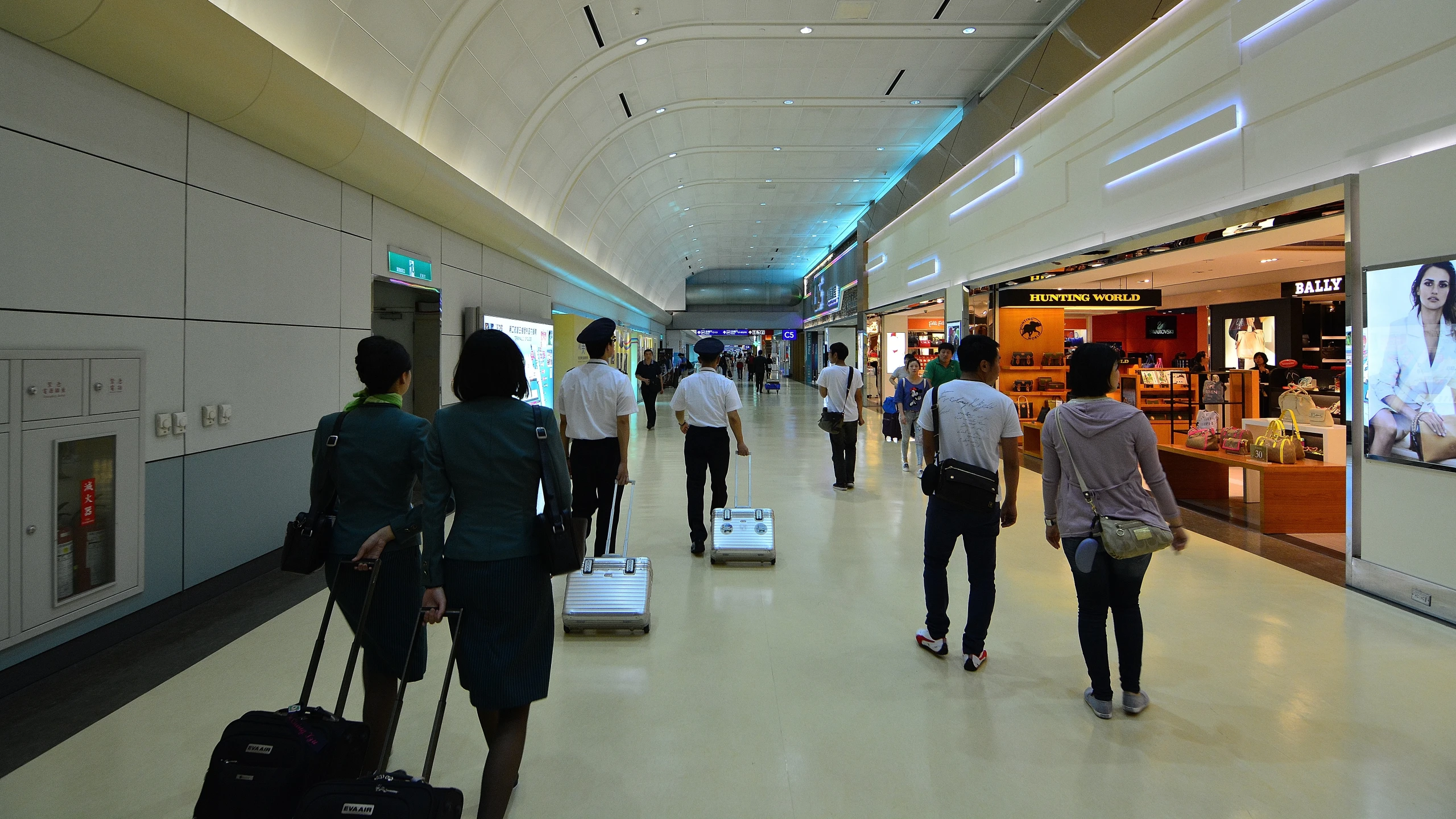 people in a airport walking through an empty walkway