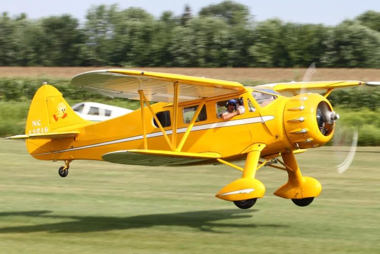 an old yellow airplane flying low by itself