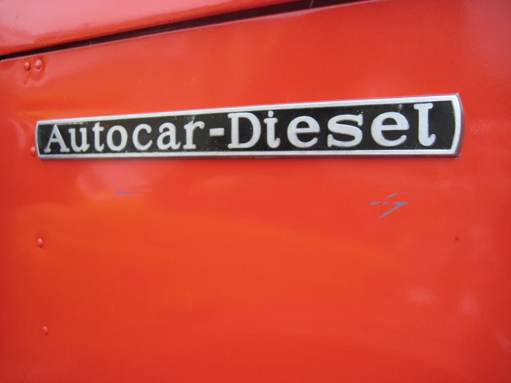an orange, car - diesel, with a sign stating autocar diesel