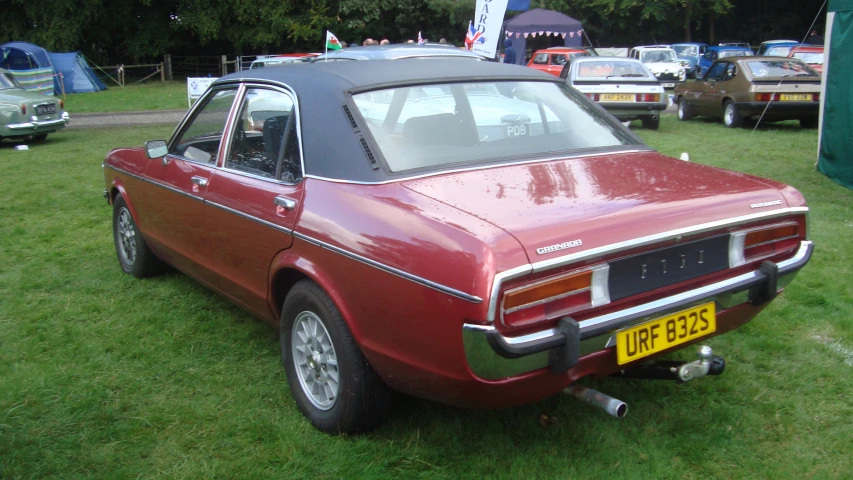 a red car is parked in some grass