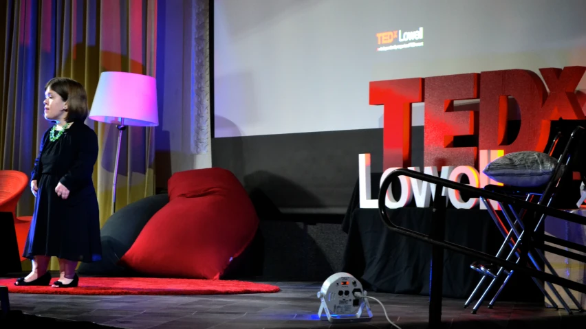 a woman standing on a stage near a red chair