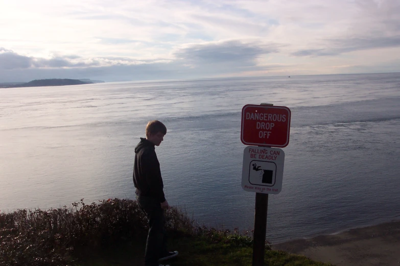 a man standing next to a street sign that warns about dingkers