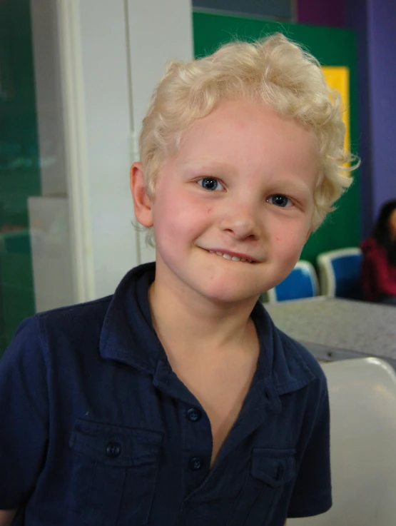 a boy in a blue shirt smiles at the camera