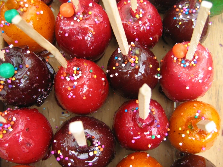 some apples are sitting next to wooden dows with colored sprinkles