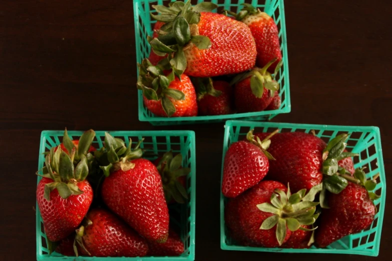 the strawberries are sitting in the green plastic baskets