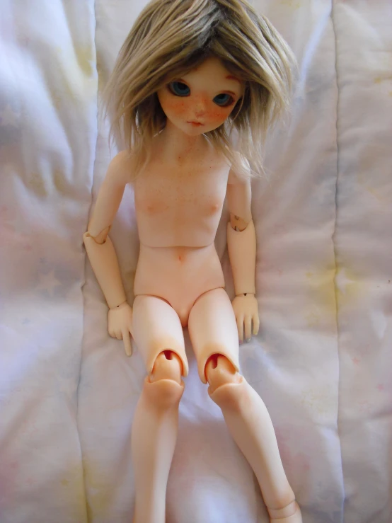 a small  doll sits on a blanket