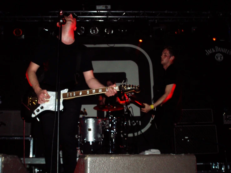 two musicians are on stage while one plays a guitar