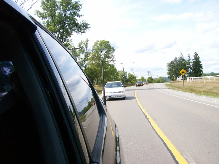 the back view of cars driving down a country road