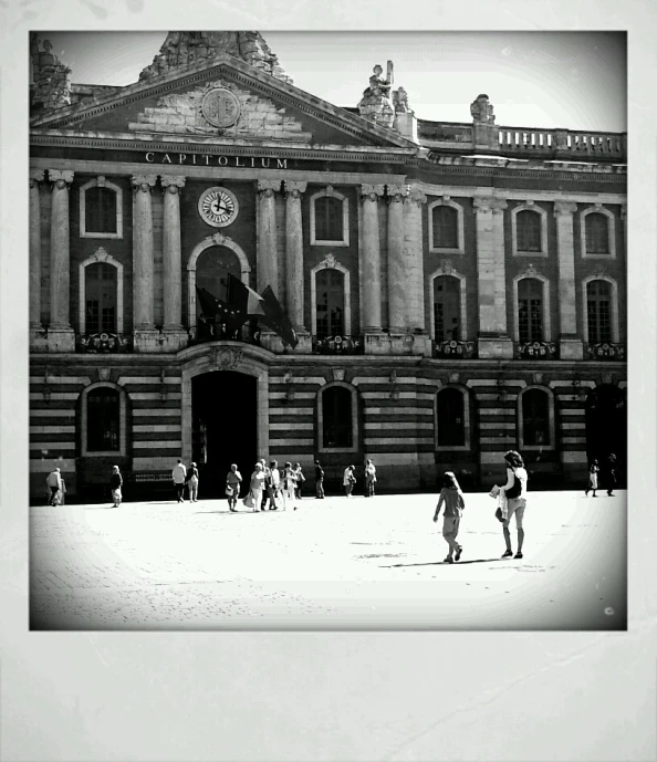 black and white image of people walking in front of an old building