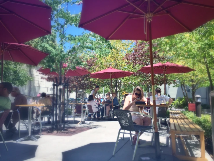 a woman sitting outside under an umbrella while a man walks in the distance