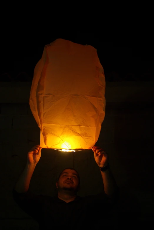 a man holding up a paper lantern over his head