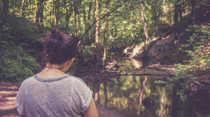 girl standing by small stream looking down at stream