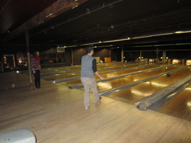 two people in an empty bowling alley holding paddles