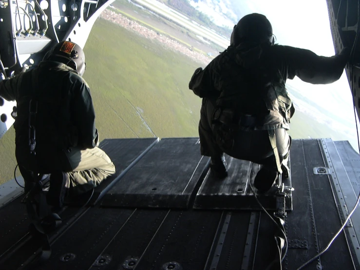 two men are sitting on a glider watching the ground