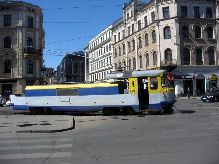 a train sitting on top of a road near tall buildings