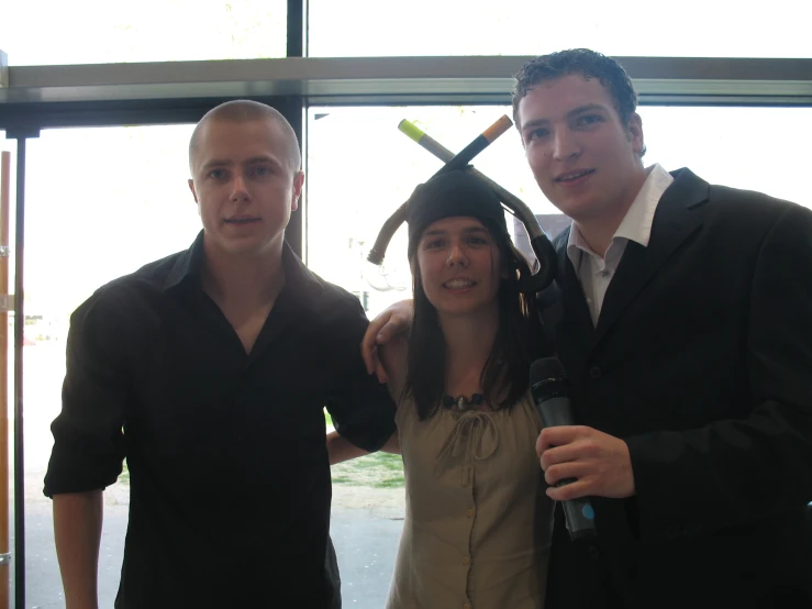 three people stand together and one holds up his graduation cap