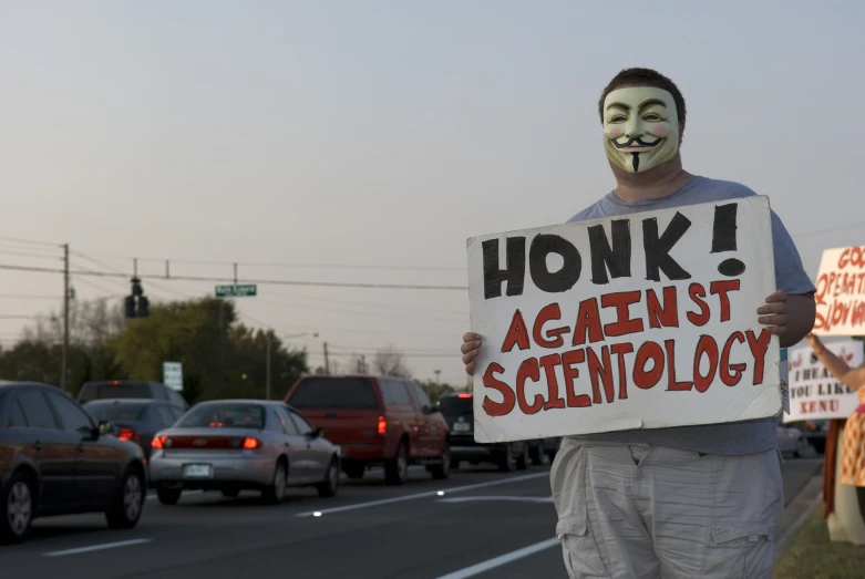 a man with green painted face and holding a sign