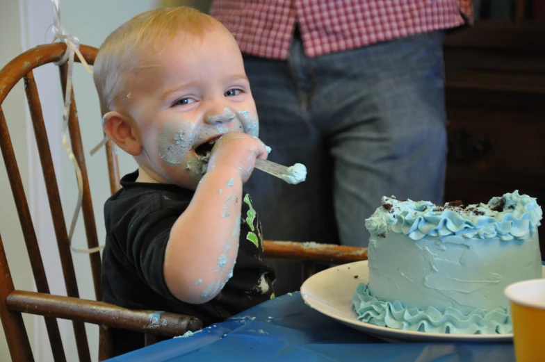 a  in black shirt brushing his teeth by cake