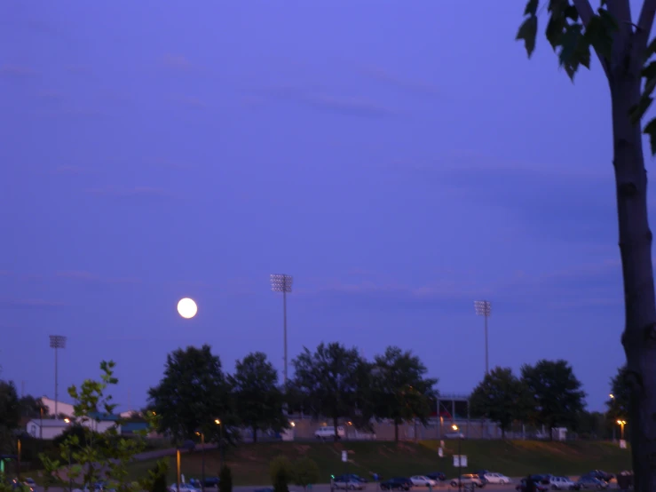 a full moon rises over the football field