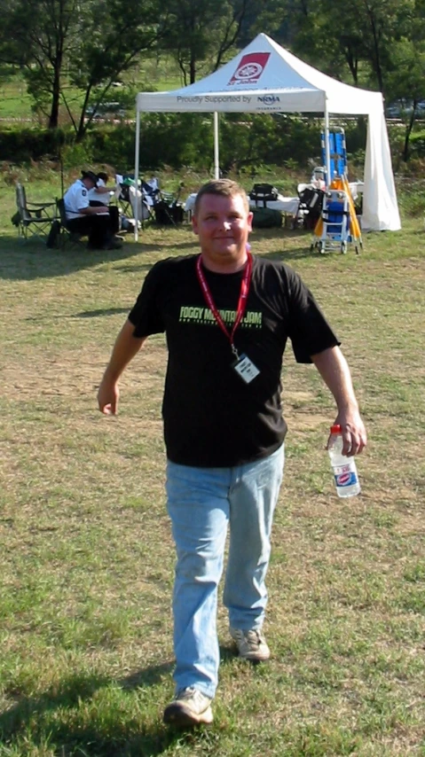 a man with a bottle standing in the grass next to another man