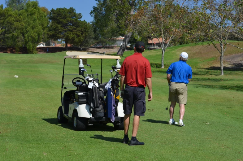 two men are standing around the golf cart