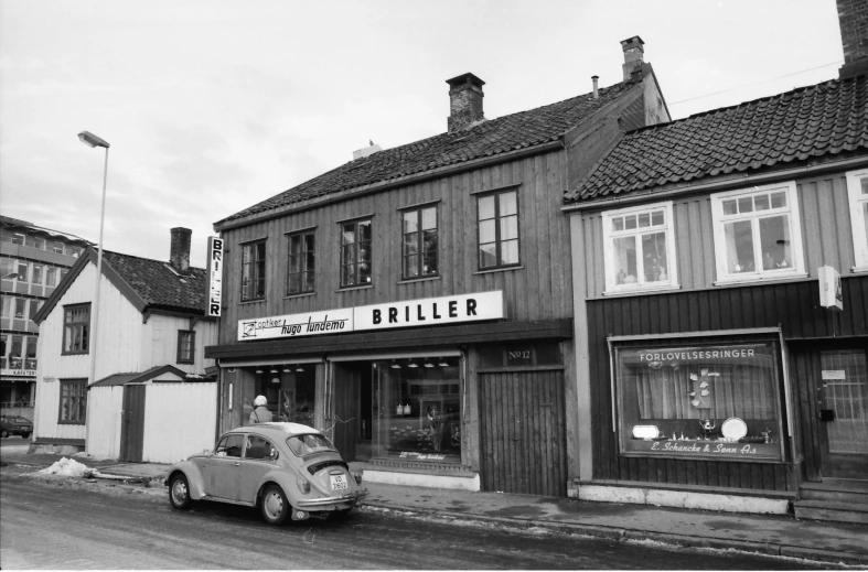 there is a small old car parked outside a store